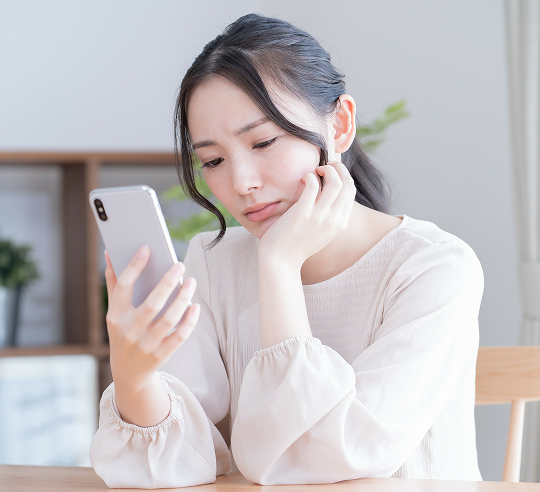 スマートフォンを見つめ困っている様子の女性