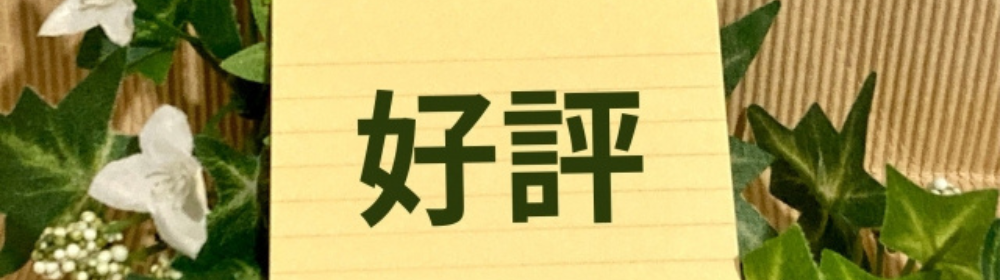観葉植物に囲まれた背景の中、黄色いメモ用紙に『好評』と書かれたカードが目立つイメージ