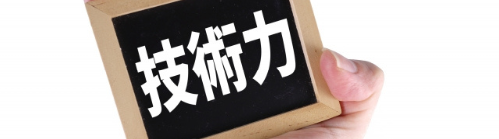 黒板風のプレートに『技術力』と白文字で書かれたものを手に持っている様子