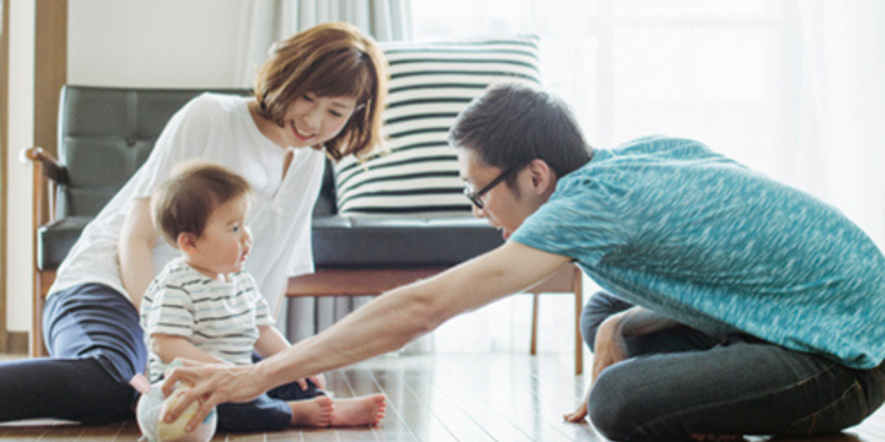 明るい室内で小さな子どもと遊ぶ若い夫婦