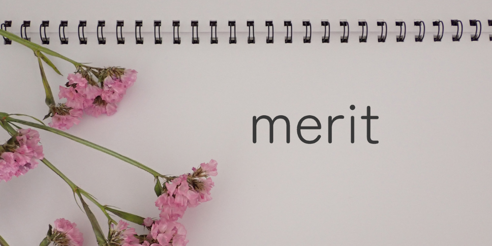 ノートと花とともに「merit」と書かれたイメージ