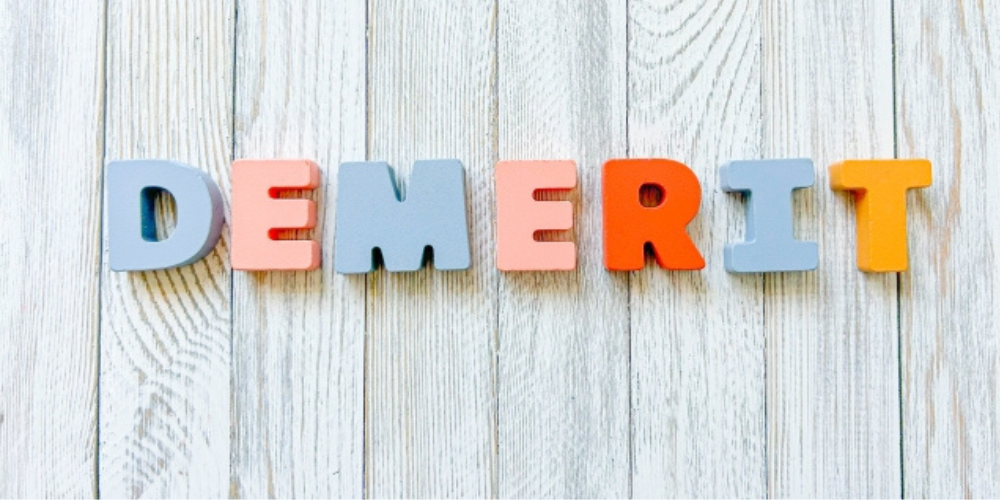 木目の背景の上に「DEMERIT」とカラフルな文字が並べられている