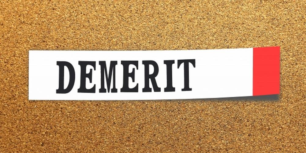 「コルクボードに貼られた『DEMERIT』の文字が書かれた白い紙」