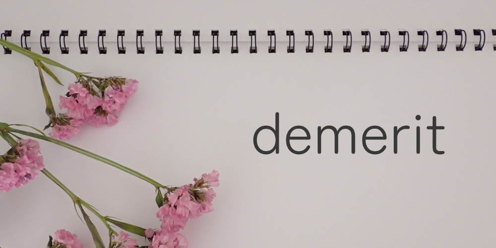 ノートに書かれた「demerit」の文字とピンクの花