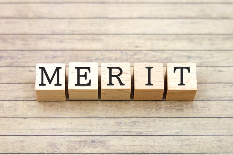 「木目の背景に『MERIT』と書かれた木製ブロックが並べられているイメージ写真」