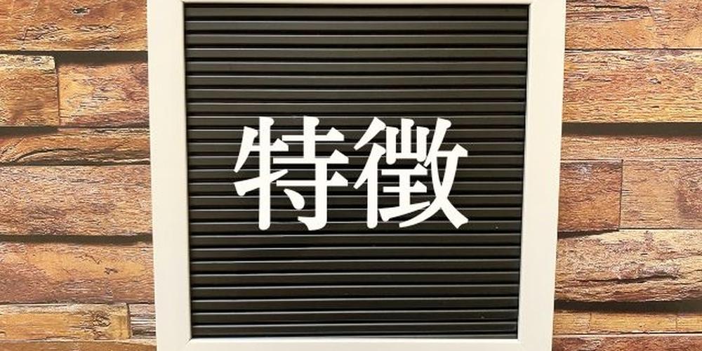 木目調の壁を背景に、「特徴」と書かれた黒いボードが掛けられているイメージ