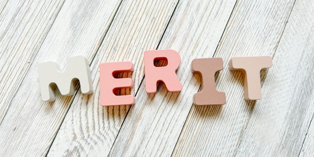 白木の床の上に「MERIT」と並べられた淡い色のアルファベットブロックのイメージ