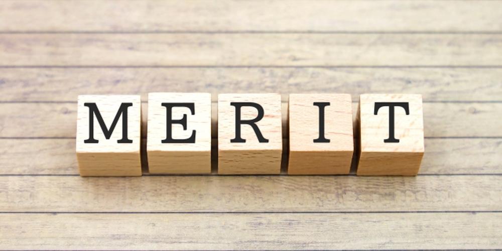 木目調の背景に「MERIT」と書かれた木製ブロックが並べられているイメージ