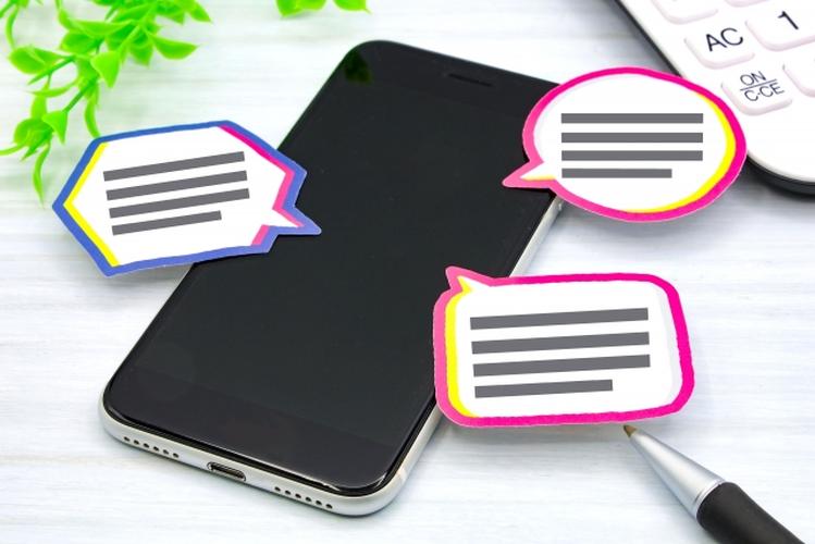 スマートフォンの周囲に配置されたカラフルな吹き出し型のコメントカード、コミュニケーションや口コミを表現するイメージ