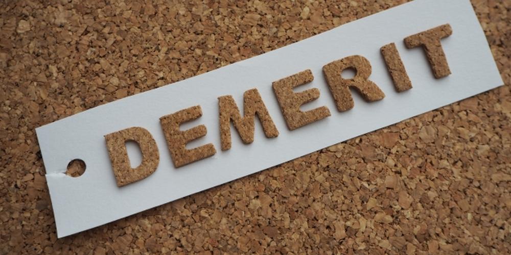 コルク素材で「DEMERIT」と書かれた文字が白いタグの上に置かれているイメージ