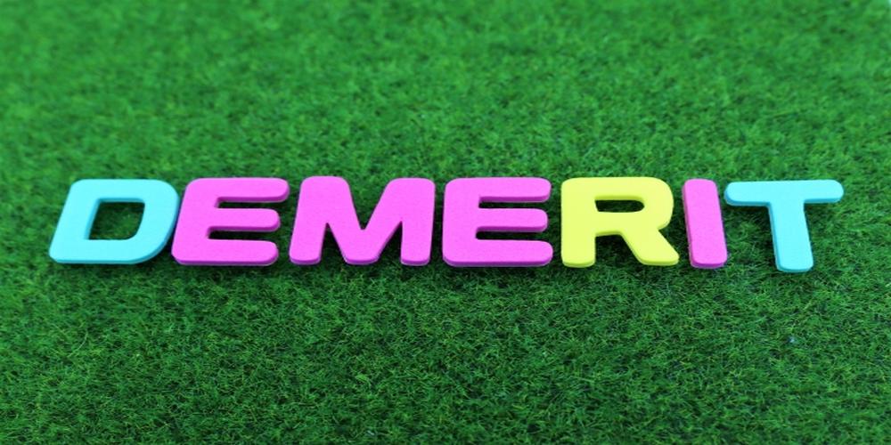  緑の芝生の上にカラフルなアルファベットで「DEMERIT」と並べられた文字。