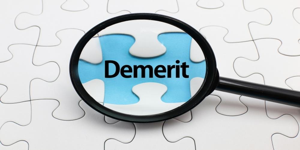 パズルのピースの上に「Demerit」の文字が拡大鏡で強調されたイメージ。