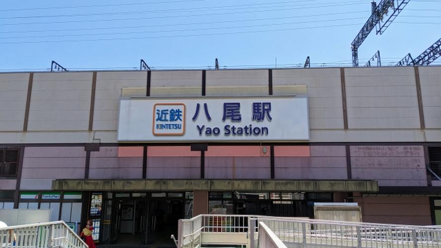 「近鉄八尾駅の駅舎外観 – 正面に駅名サインとファミリーマートが見える