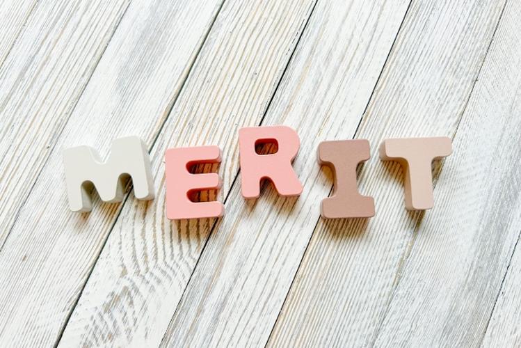 白木調の床にパステル調のブロックで『MERIT』と表現されたやわらかい印象の構成