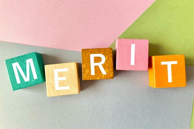 「カラフルな背景に並べられた『MERIT』の文字入り木製ブロック、明るくポップな雰囲気のイメージ」