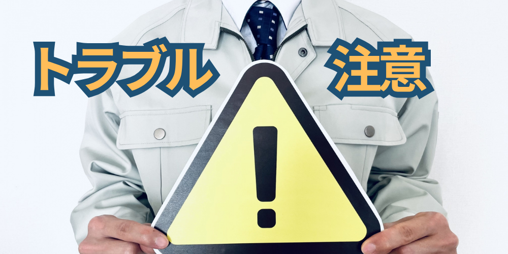 作業服の人が黄色い警告マークを掲げ、「トラブル注意」と重ねた注意喚起バナー