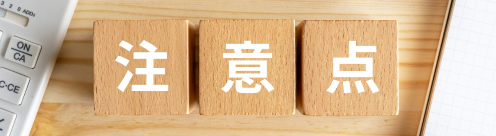 電卓とノートのそばに置かれた「注意点」と書かれた木製ブロック