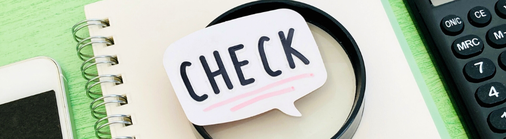 虫眼鏡と「CHECK」の吹き出し、電卓やスマホなどの小物が置かれている