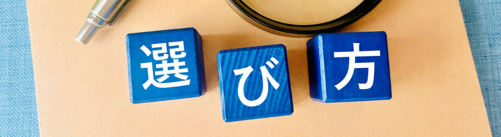 ペンと虫眼鏡のそばに置かれた「選び方」と書かれた青い木製ブロック