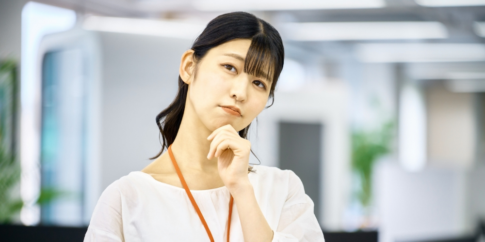 オフィスで顎に手をあて、何かを真剣に考えている若いビジネスウーマン