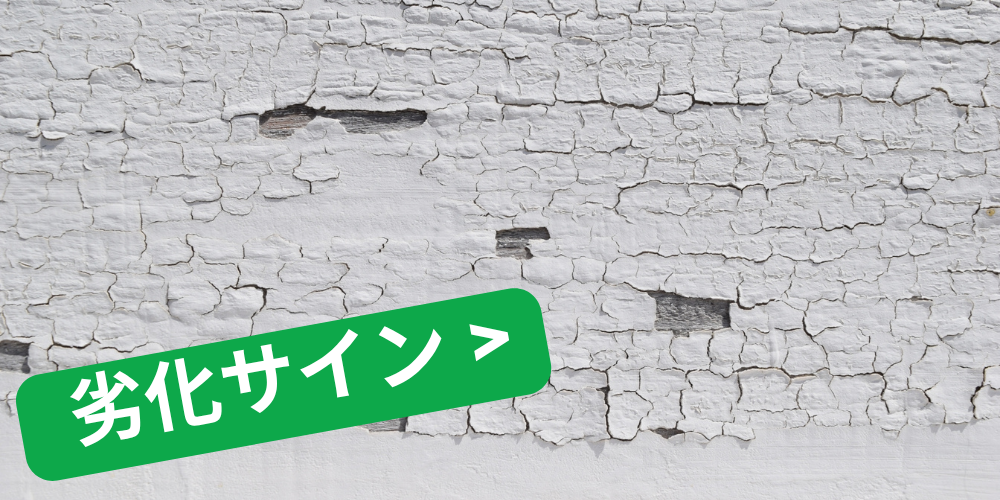 ひび割れと剥離が目立つ白い外壁に「劣化サイン >」の緑ラベルが重なったイメージ図