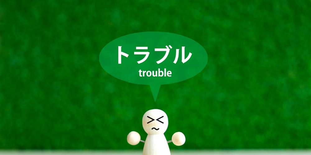「トラブル」と吹き出す困り顔の木製人形
