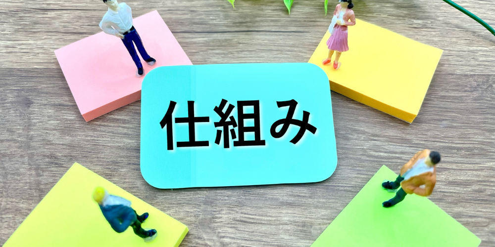 「仕組」と書かれたカードの周りに、付箋とミニチュアの人形が置かれている