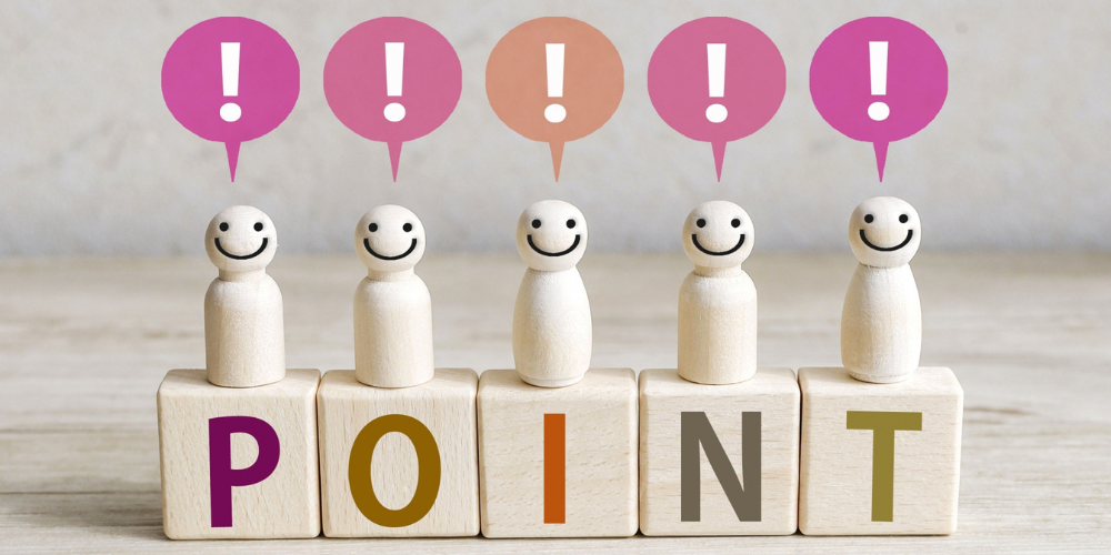 「POINT」と書かれた積み木の上に、笑顔の木製人形とビックリマークの吹き出しが並んでいる