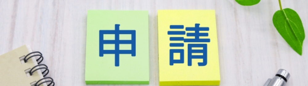 ノートとペンの横に「申請」と書かれたカラフルなブロックの画像
