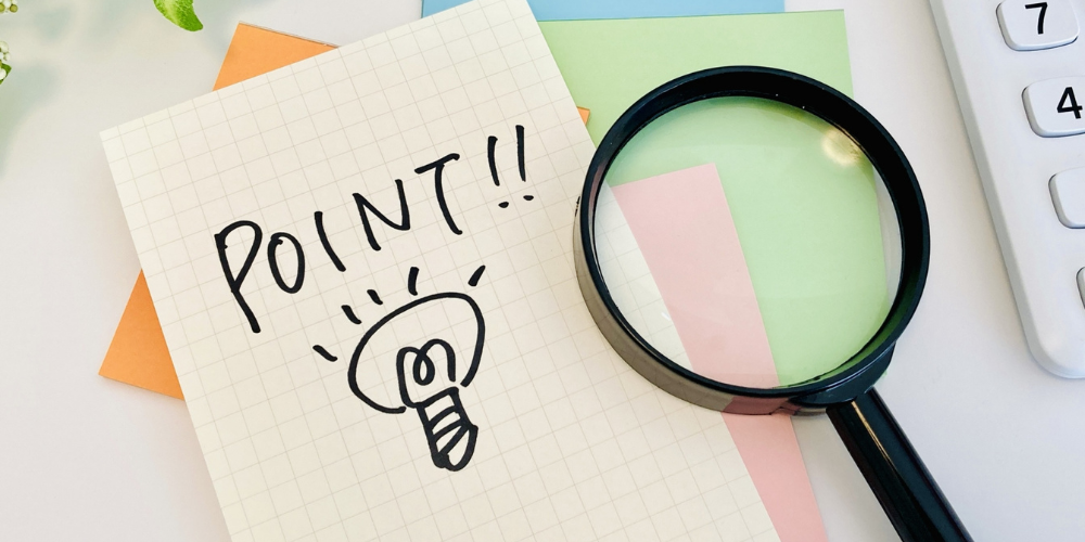 「POINT!!」と電球のイラストが描かれたメモと虫眼鏡が置かれた、重要なポイントを示す画像