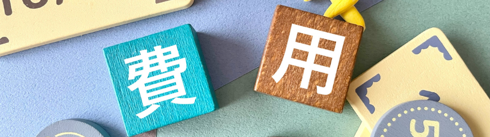 木製ブロックに「費用」と書かれた文字とカラフルなコインのイラスト