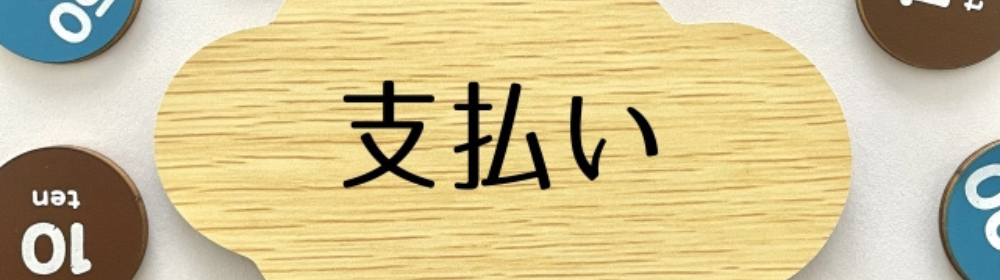 「支払い」と書かれた木製プレートと周囲に散らばる硬貨風のチップの画像