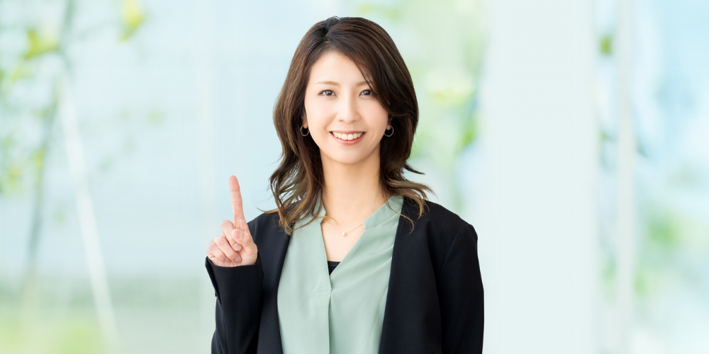 明るいオフィスで人差し指を立ててポイントを示す笑顔のビジネスウーマン