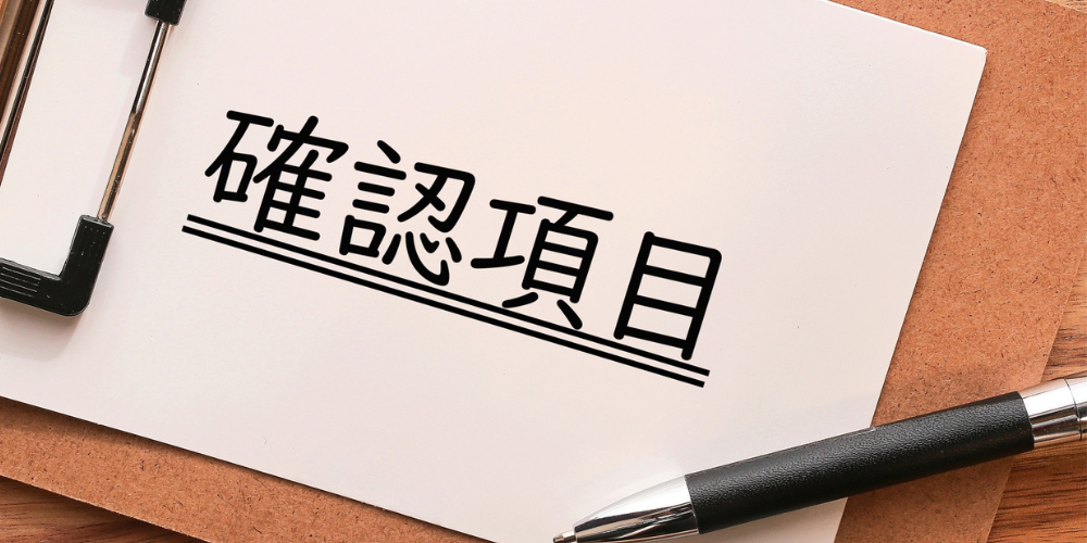 クリップボードの用紙に太字で「確認項目」と書かれ、横にボールペンが置かれたチェックリスト
