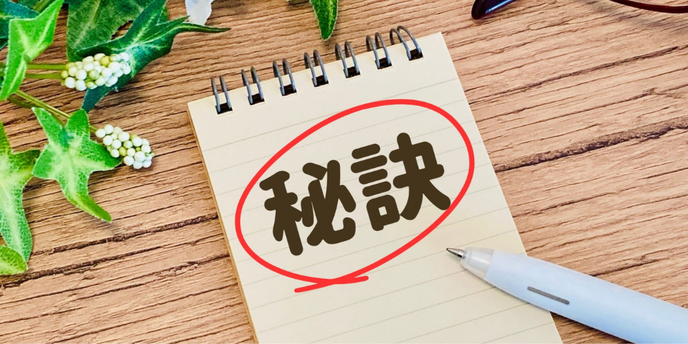 メモ帳に「秘訣」と赤丸で強調、ペンと観葉植物添え