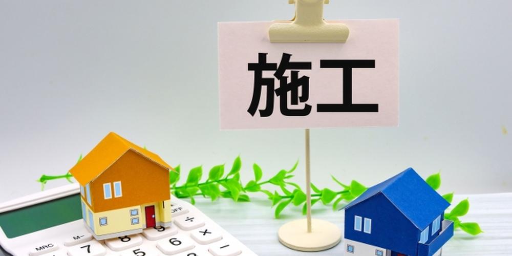 施工に関するイメージ。住宅模型と電卓、施工の文字が書かれたメモ。