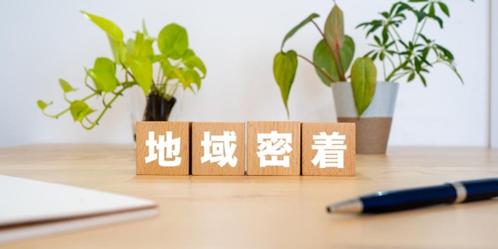 地域密着と書かれた木製ブロックと観葉植物が並ぶテーブルのイメージ
