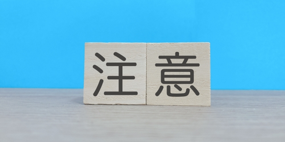 青い背景に木製ブロックで「注意」と書かれた注意喚起のイメージ画像