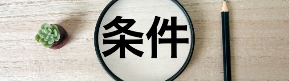 丸いフレームに「条件」と書かれた文字と黒い鉛筆、横に多肉植物が置かれた整ったデスクの上