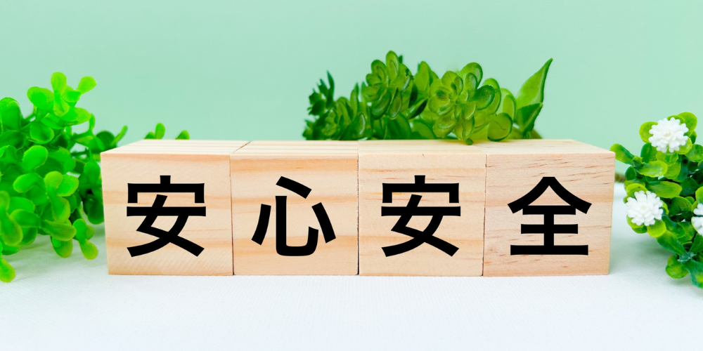 緑色の葉を背景に、木製ブロック4つに黒字で「安」「心」「安」「全」と並べた安心・安全強調イメージ