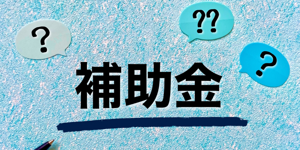 水色のテクスチャ背景に3つのカラフルな吹き出しが浮かび、その中央に太字の黒文字で「補助金」と書かれている