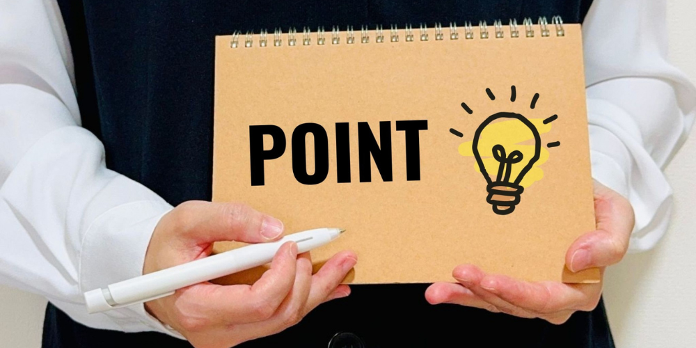黒いスケッチブックを持つ人物の前で、「POINT」と大きく黒字で書かれたパッドに電球アイコンが描かれた注目ポイント提示イメージ