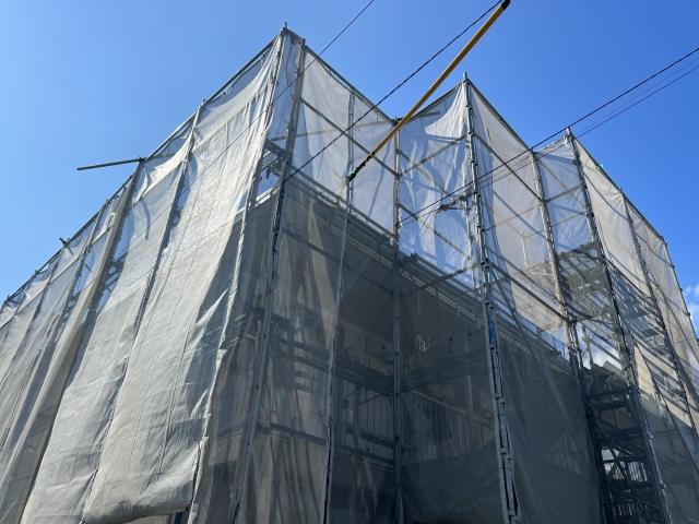 足場とシートに囲まれたアパート