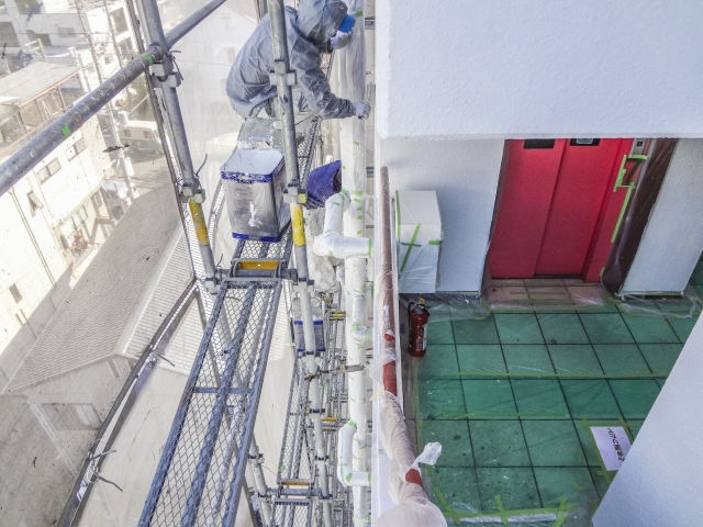 集合住宅街尾へ気を塗装している作業員